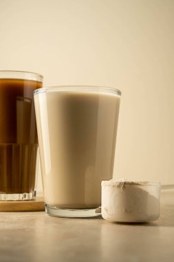 Bir kepçedeki protein tozu ve bir bardak protein içeceği. Vücut geliştirme, fitness sporu, sağlık ve beslenme