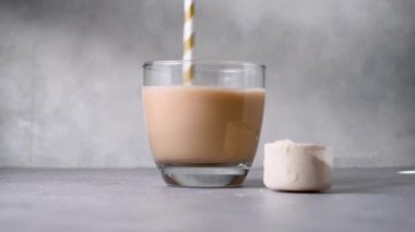 Bir kepçedeki protein tozu, bir bardak protein içeceğini karıştırıyor. Vücut geliştirme, fitness sporu, sağlık ve beslenme