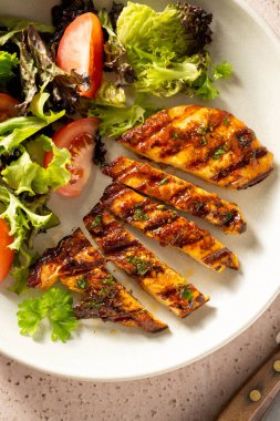 Izgara tavuk göğsü ve tabakta taze salata.
