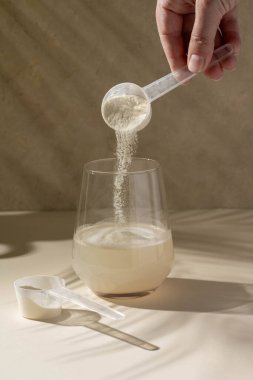 Protein tozu bir bardak suyla ölçülen kepçeyle eklendi. Beslenme ve gıda takviyesi.