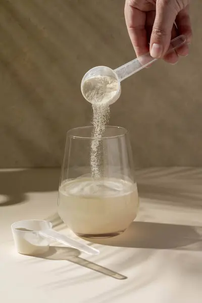 Protein tozu bir bardak suyla ölçülen kepçeyle eklendi. Beslenme ve gıda takviyesi.