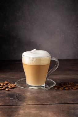 Cups of coffee drink, latte or mocha with milk foam. Glass mug, dark wooden background.