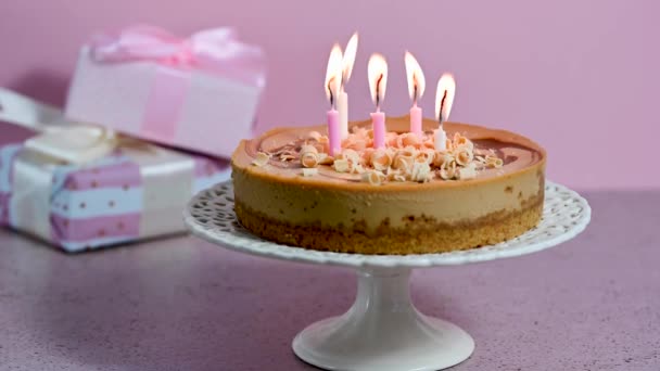 含盐焦糖芝士蛋糕 点着蜡烛 礼品盒 粉色背景 高质量的4K镜头 — 图库视频影像
