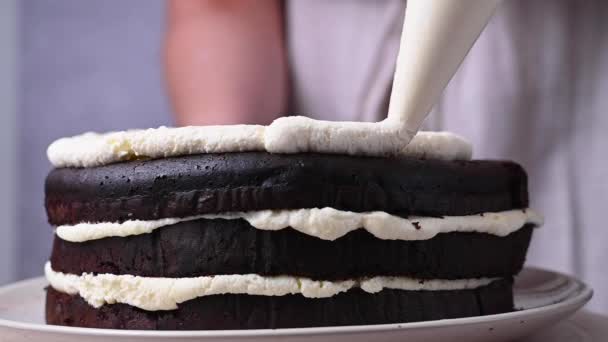 家で焼いたケーキを飾る スポンジケーキにホイップクリームを配管する女性の手 — ストック動画