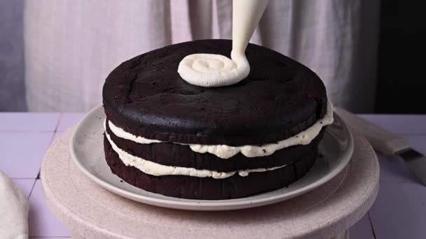 装饰家烤巧克力蛋糕 女的手在海绵蛋糕上喷出奶油 — 图库视频影像