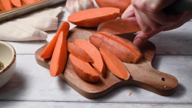 Tatlı patates dilimleri pişirmek, kadın elleri kesme tahtasındaki çiğ patatesleri dilimlemek