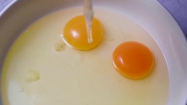 Raw egg yolk dripping down in a bowl. Cooking pastry or breakfast. Protein food.