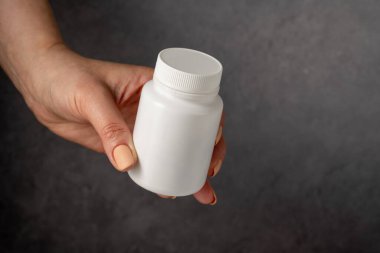 Beyaz plastik şişede antibiyotik hapları ve bir bardak su. Kapsüller, kolajen, vitaminler, ağrı kesiciler veya ilaçlar.