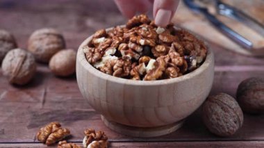 Ceviz çekirdeği. Tahta kaseden ceviz toplayan kadın, sağlıklı protein atıştırmalığı..