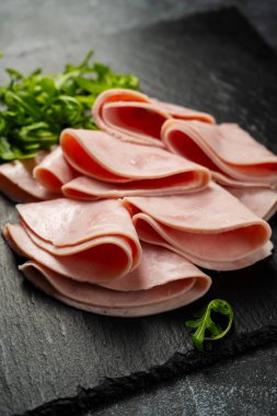 Kapalı jambon dilimleri koyu arkaplanda.