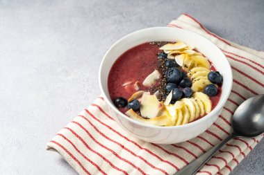 Meyve suyu kasesi, taze yaban mersini, ahududu, muz ve chia tohumlu çilekli smoothie..