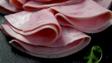 Koyu arkaplanda lezzetli jambon dilimleri var..
