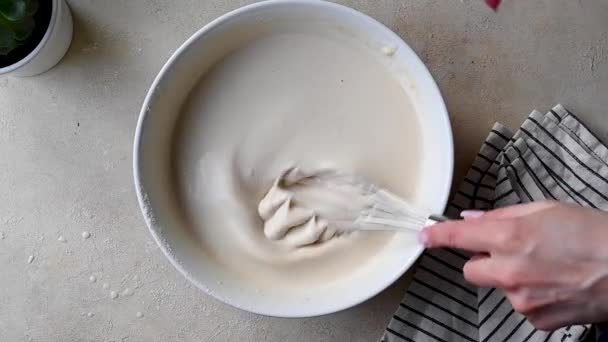パンケーキやケーキのためのボウルで生地のバッテリーを白くする女性の手 トップビュー — ストック動画