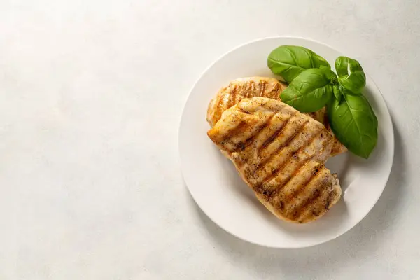Grilled chicken fillet in a plate, on white background.