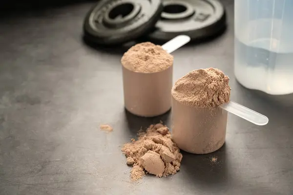 Chocolate protein powder in scoops. Food supplement, nutrition.