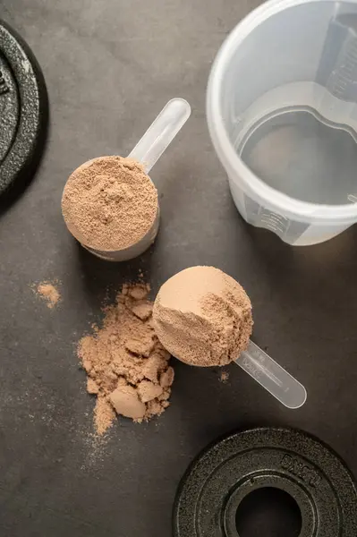 Chocolate protein powder in scoops. Food supplement, nutrition.