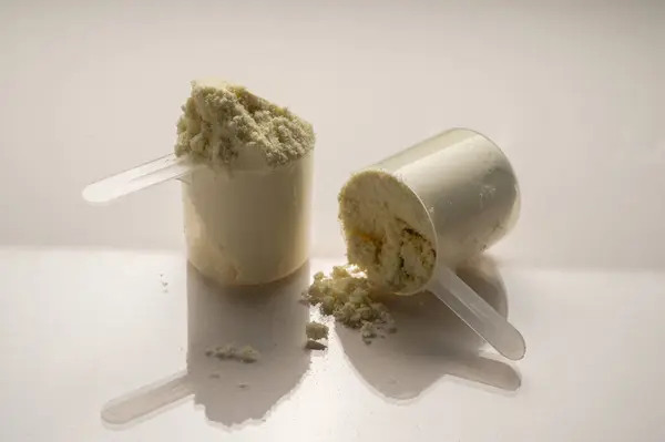 Vanilla protein powder in scoops. Food supplement, nutrition.