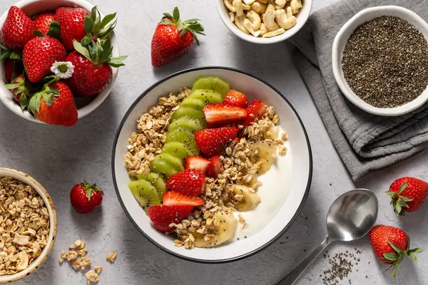 Yoğurtlu granola, taze çilek, kivi, muz ve fındık, tohum. Sağlıklı kahvaltı.