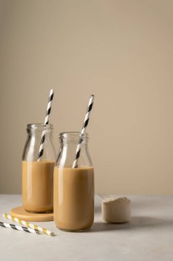 Chocolate protein drinks in glass bottles with paper straw clipart