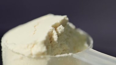 Bir kepçedeki protein tozu, makro atış. Yiyecek takviyesi. Karanlık arka plan. Vücut geliştirme, fitness, spor salonu