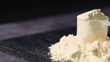 Bir kepçedeki protein tozu yığını. Yiyecek takviyesi. Karanlık arka plan. Vücut geliştirme, fitness, spor salonu