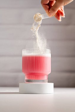 Kolajen protein tozu. Bardağa pembe protein tozu döküyorum.