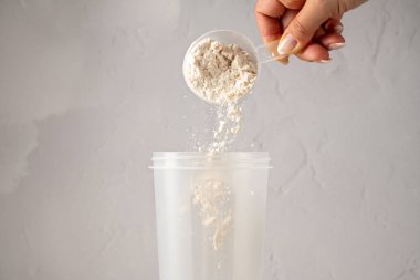 Bir kepçedeki protein tozu. Çikolata protein tozunu bir karıştırıcıya döküyorum. Gıda takviyesi