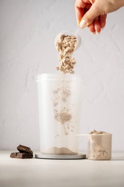 Bir kepçedeki protein tozu. Çikolata protein tozunu bir karıştırıcıya döküyorum. Gıda takviyesi