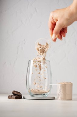 Bir kepçedeki protein tozu. Bardağa çikolata protein tozu döküyorum. Gıda takviyesi
