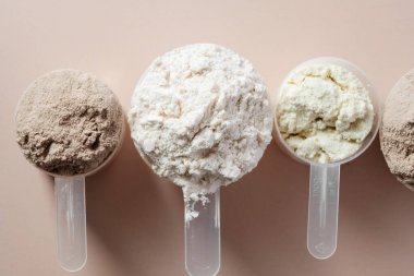 Kepçe içinde protein tozu. Sütlü protein tozunun farklı tatları, üst görünüm.