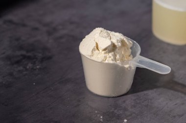 Bir kepçedeki protein tozu yığını. Yiyecek takviyesi. Karanlık arka plan. Vücut geliştirme, fitness, spor salonu