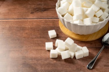 White sugar cubes on wooden background. Cooking dessert ingredient. clipart