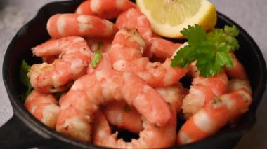 Tavada baharatlı kırmızı karides, taze otlar ve limonla servis edilir..