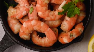 Tavada baharatlı kırmızı karides, taze otlar ve limonla servis edilir..