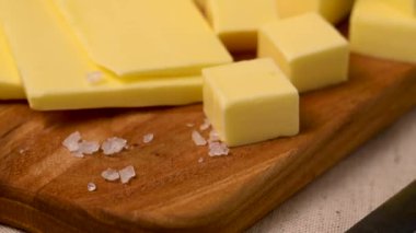 Tereyağı bloğu, çim ile beslenen tereyağı dilimleri tahta kesme tahtasında. D vitamini ve yağ kaynağı 