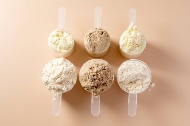 Kepçe içinde protein tozu. Sütlü protein tozunun farklı aromaları, kopyalama alanı