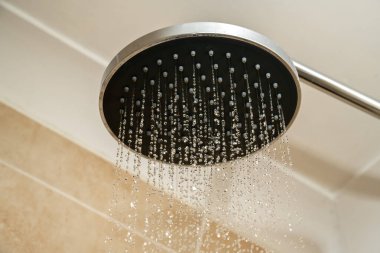 Su damlacıklarıyla krom duş başlığı. Artan su faturaları