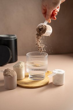 Çikolatalı protein tozu bardağa dökülüyor. Gıda desteği, fitness sporu, sağlık ve beslenme