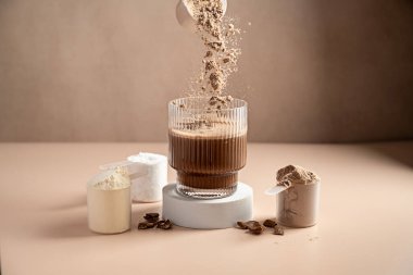 Çikolatalı protein tozu bardağa dökülüyor. Gıda desteği, fitness sporu, sağlık ve beslenme