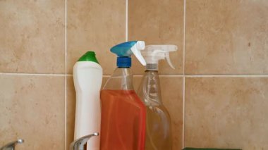 Sprey deterjan, banyo tüpü ve su musluğu, sarı eldivenler ve bez..