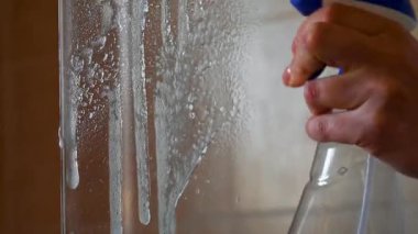 Lastik eldivenlerle cam duş perdesini temizliyorum.