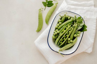 Beyaz tabakta taze bezelyeler, sağlıklı atıştırmalıklar..