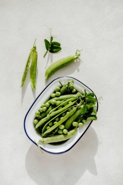 Beyaz tabakta taze bezelyeler, sağlıklı atıştırmalıklar..