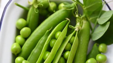 Beyaz tabakta taze bezelyeler, sağlıklı atıştırmalıklar.