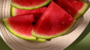 Oval tabakta taze karpuz meyvesi dilimleri, yeşil soyut arka plan..