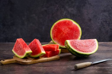 Köy ahşap masada taze karpuz dilimleri, koyu arkaplan.