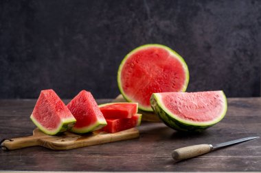 Köy ahşap masada taze karpuz dilimleri, koyu arkaplan.