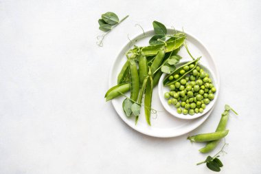 Beyaz tabakta taze bezelyeler, sağlıklı atıştırmalıklar..