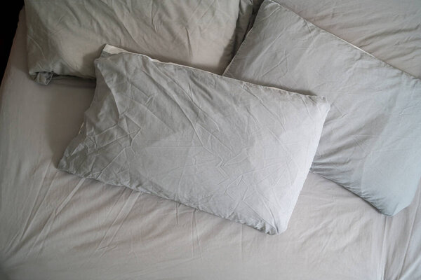 Pillows with fresh clean pillowcases, grey cotton bed sheets.