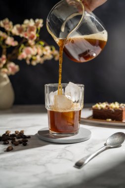 Buzlu bir bardağa koyu kahve dolduruyorum..